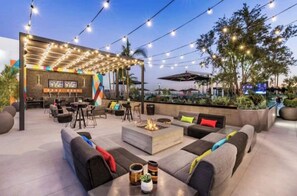 Relax by the fire pit in a serene outdoor lounge area with comfortable seating and a bar.