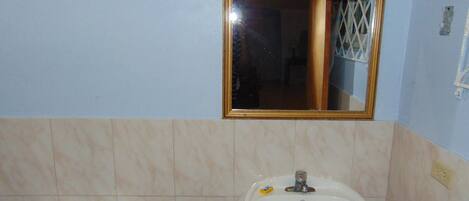 A bathroom with a toilet, sink, and a mirror.
