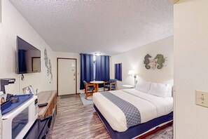 Relax in a stylish room with a neatly made bed, flat-screen TV, and comfortable workspace.