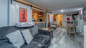 Moderni olohuone, jossa on sohva, sohvapöytä ja taustalla keittiötila.