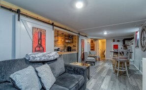 Uma sala de estar moderna com sofá, mesa de centro e cozinha ao fundo.