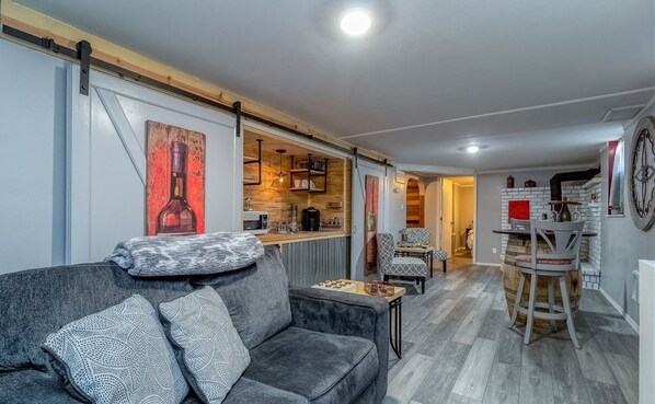 Una sala de estar moderna con un sofá, una mesa de centro y una zona de cocina al fondo.