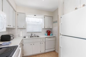A compact kitchen with white cabinetry, a toaster, a coffee maker, and a dishwasher.