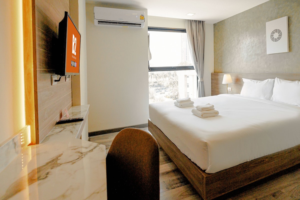 Une chambre d’hôtel avec un grand lit, une télévision, la climatisation et une vue sur l’extérieur.