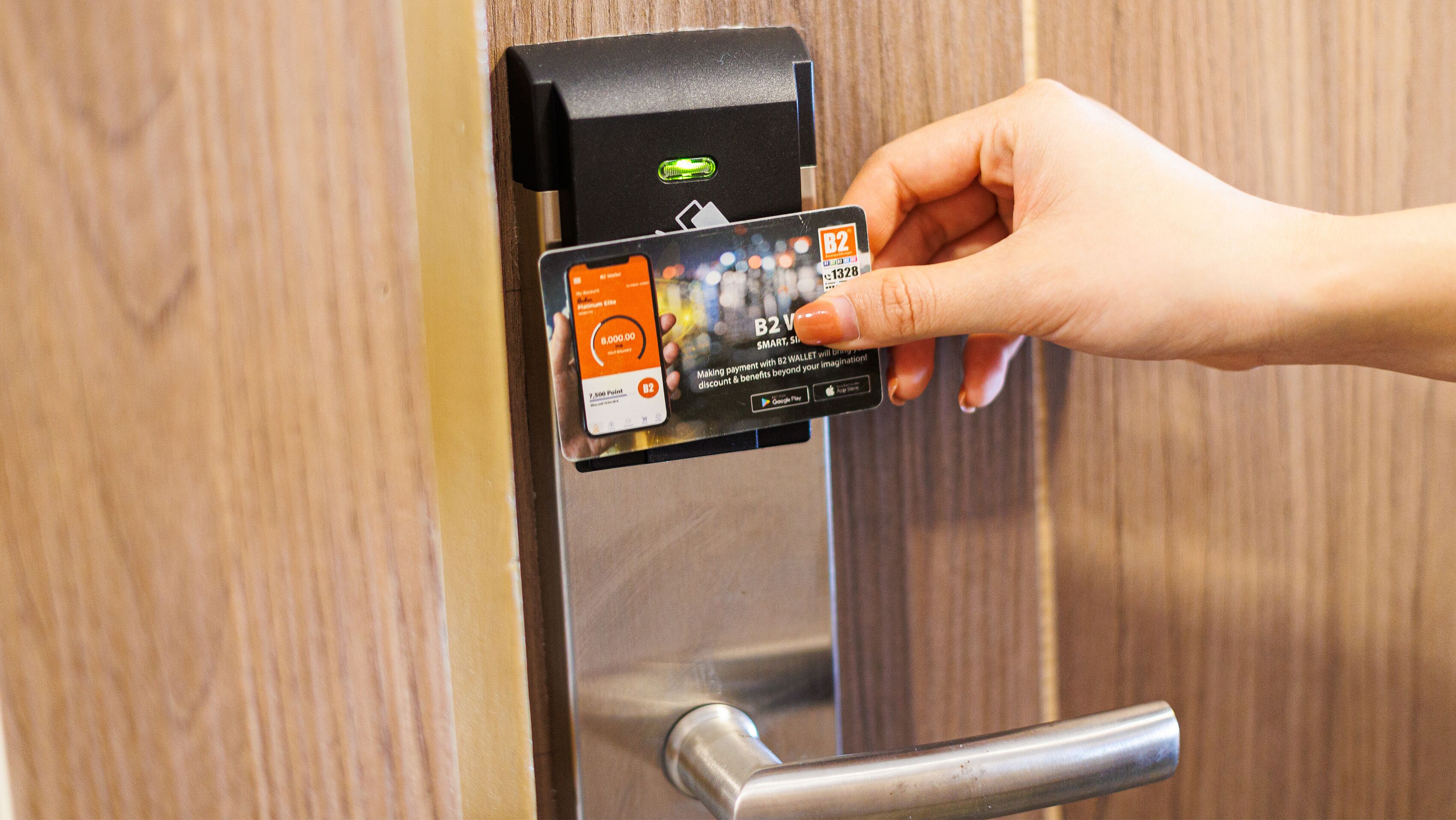 A hand holding a B2 V card near a door with a biometric fingerprint scanner.
