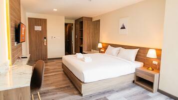 Ein Hotelzimmer mit Bett, Nachttischlampen, Schreibtisch und Fernseher.