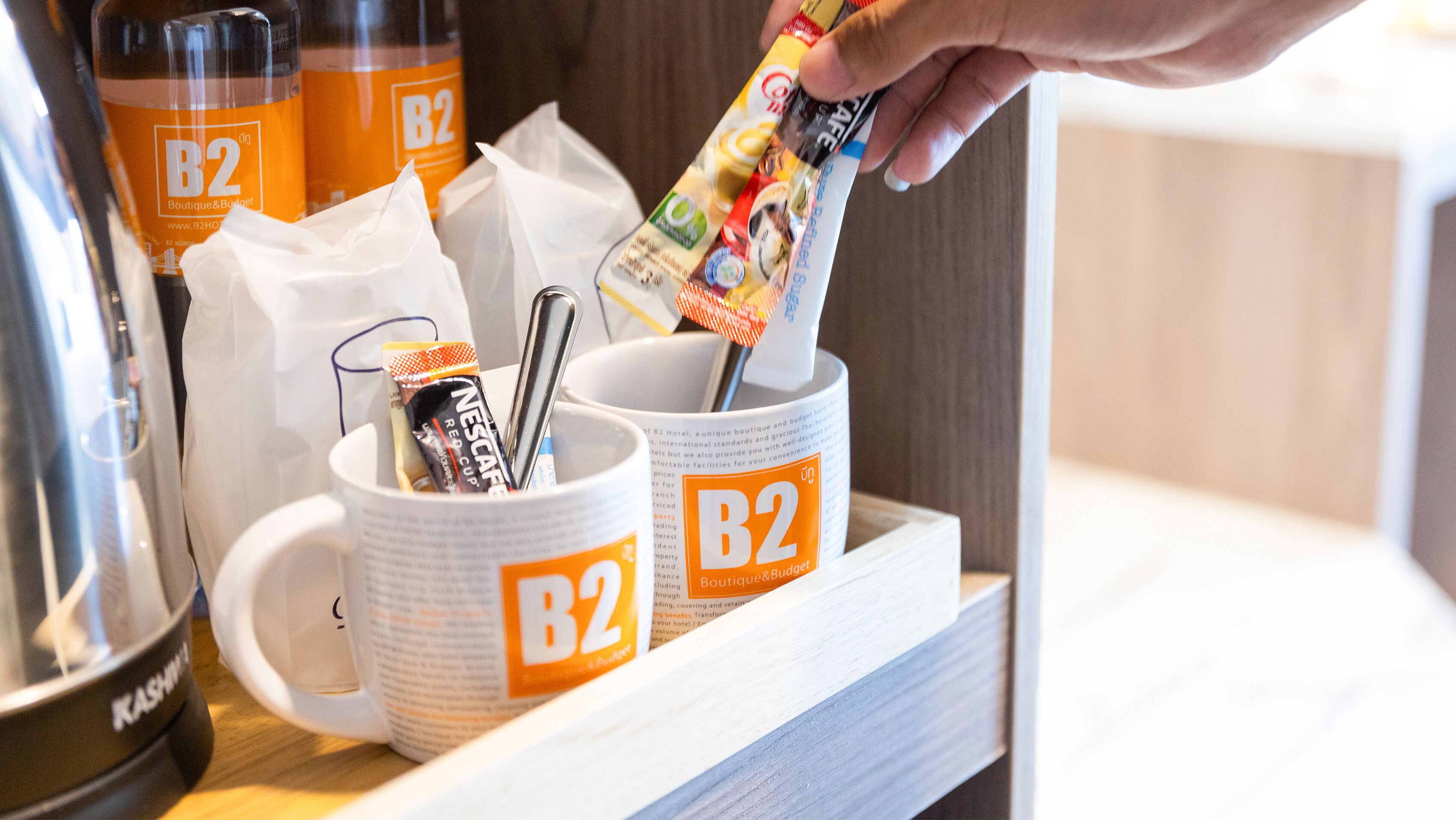 A B2 branded coffee station with disposable cups and a spoon.