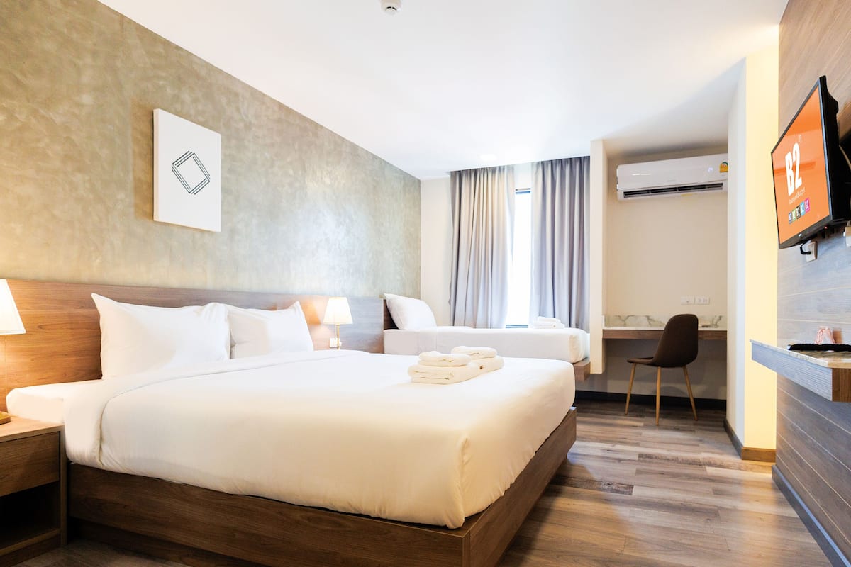 Une chambre d’hôtel avec un grand lit, un bureau, une chaise, une télévision et une salle de bain équipée d’un climatiseur.
