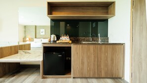 A compact kitchen with a built-in refrigerator, wooden cabinetry, and a countertop with a coffee maker and bottles. - B2 Khon Kaen Premier Hotel (Khon Kaen)