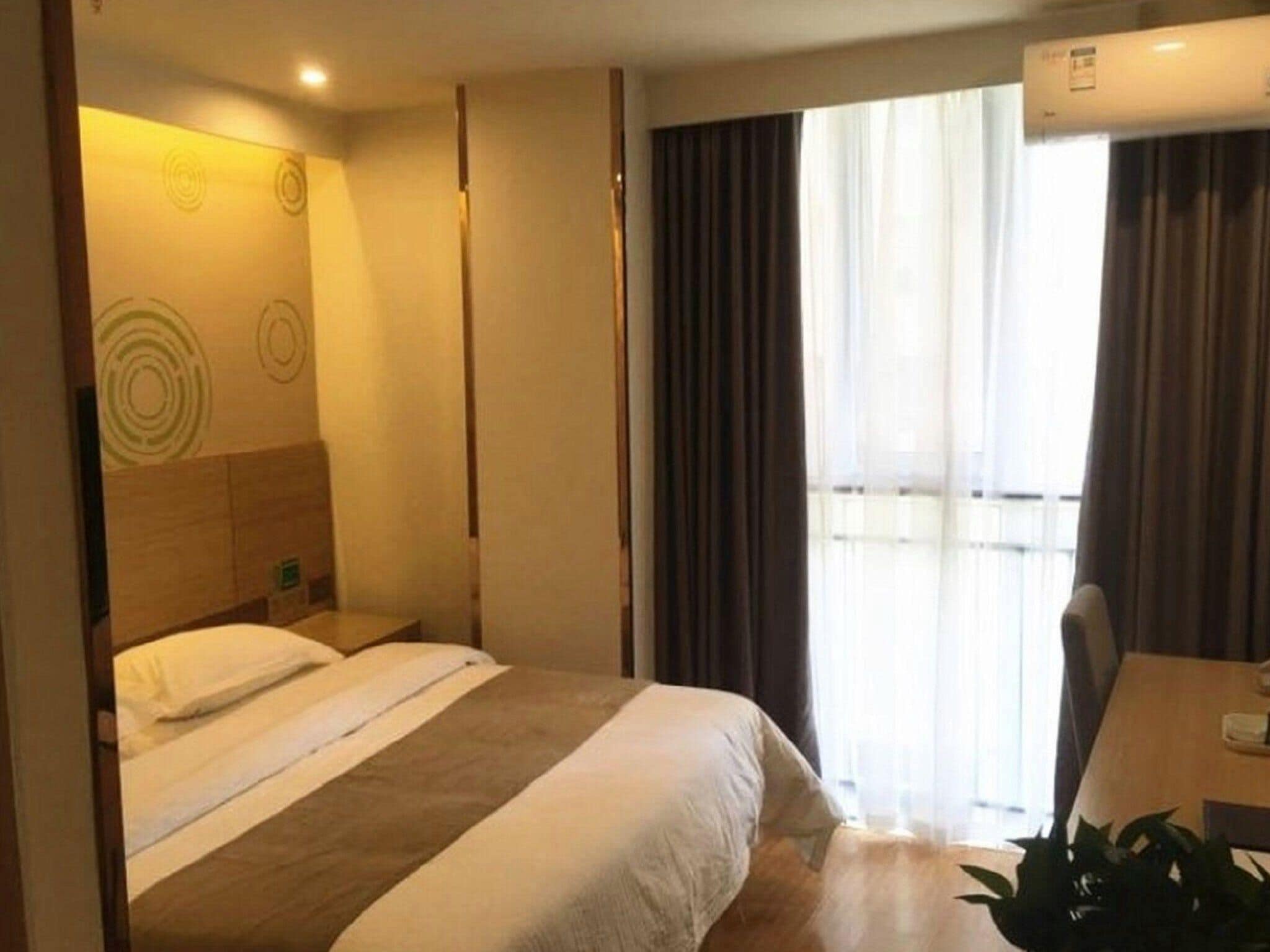 Habitación de hotel con cama, escritorio y ventana con cortinas.