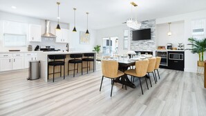 Una cucina moderna con isola centrale, illuminazione a sospensione e zona pranzo con sedie.