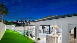 Un'area esterna moderna con piscina, posti a sedere e un patio ben illuminato.