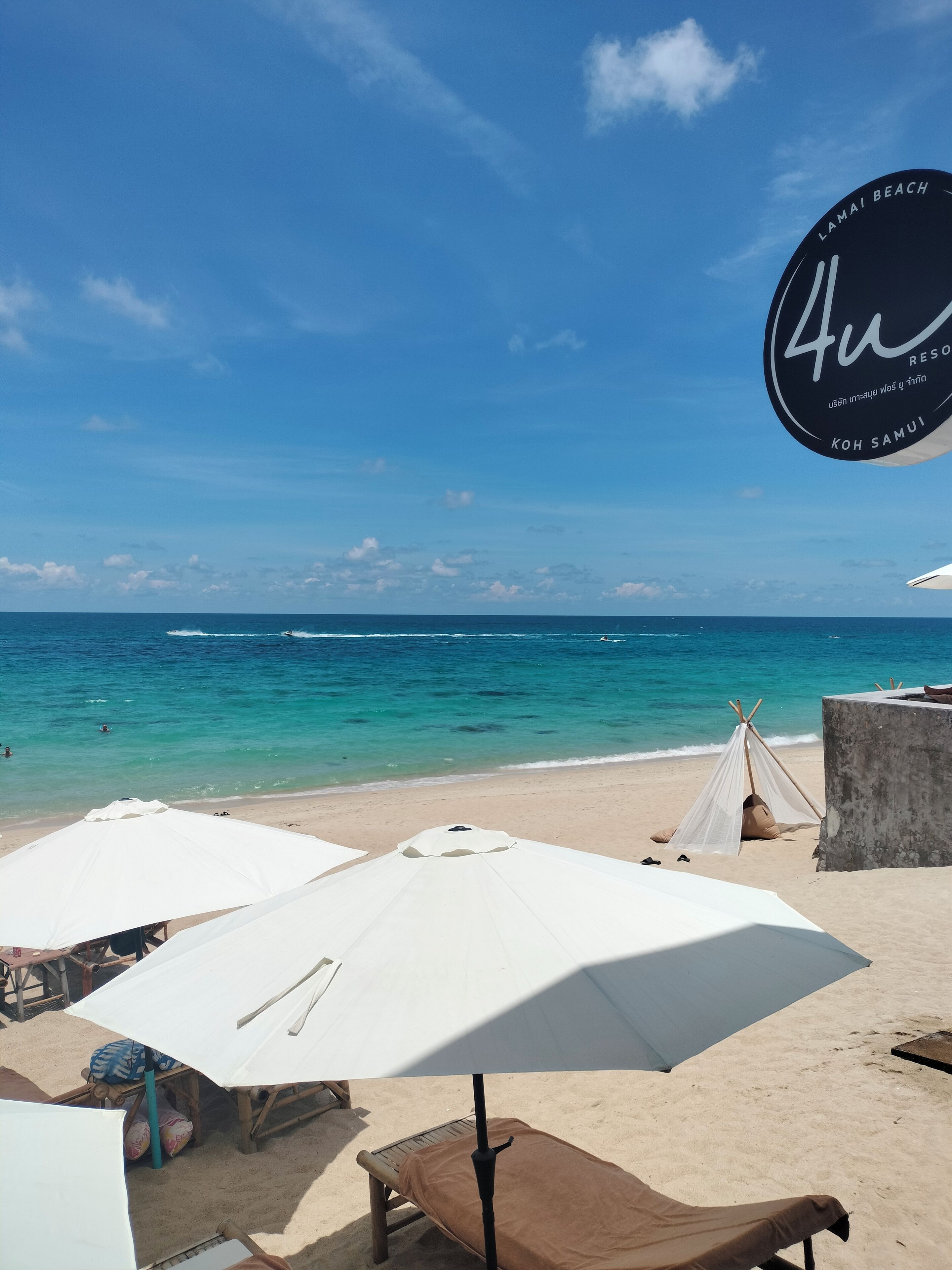A beach with umbrellas, a tent, and a lounge chair.