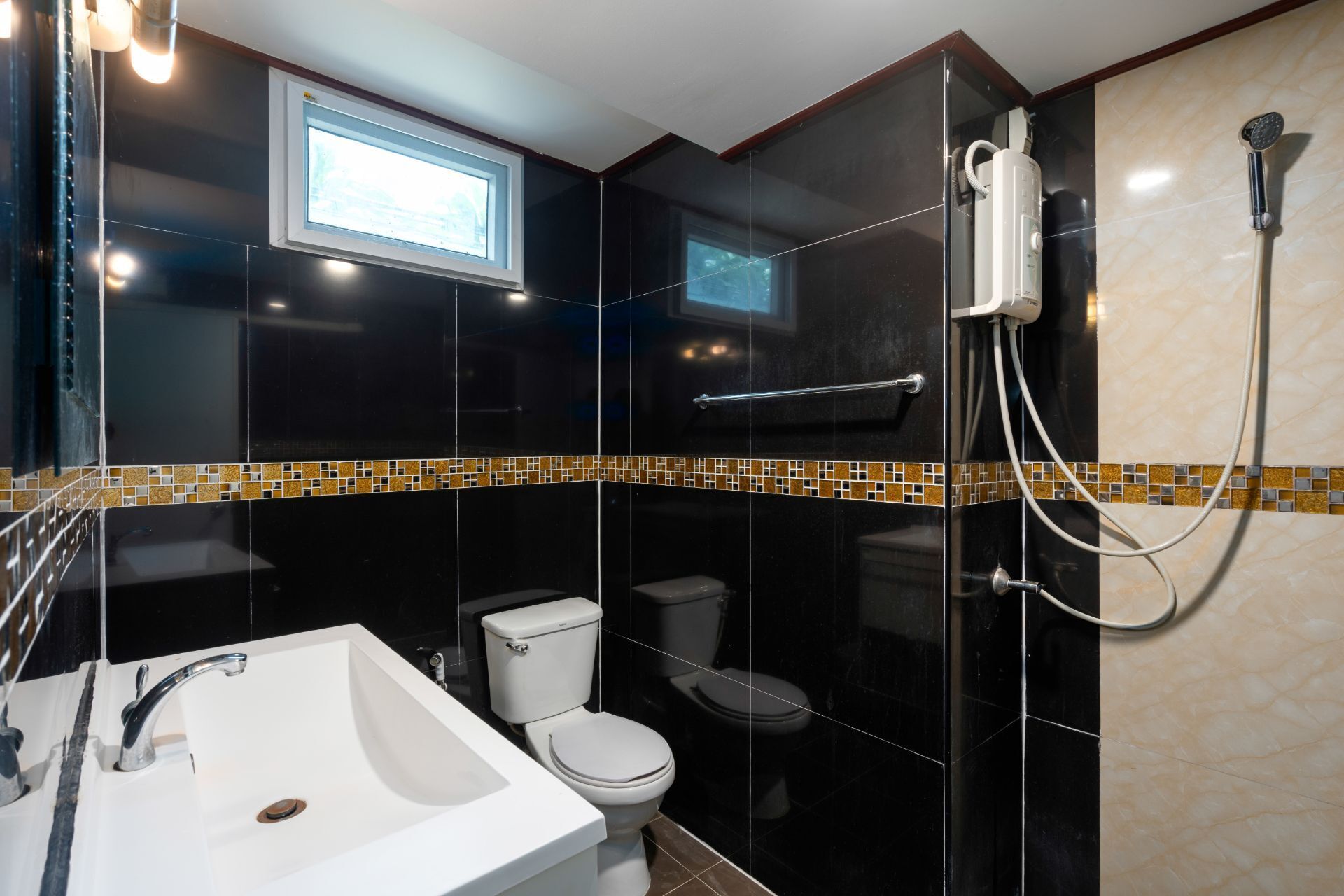 A modern bathroom with a glass-enclosed shower, a white sink, and a toilet.