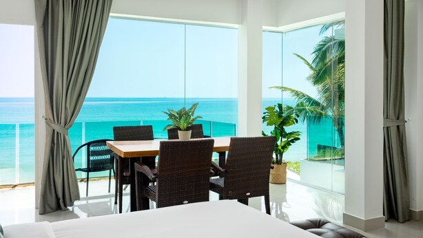 A room with a large window overlooking a turquoise sea, furnished with a table and chairs, and a potted plant. - 4U Resort Samui (Koh Samui)