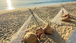 A beach with hammocks and pillows on the sand. - 4U Resort Samui (Koh Samui)