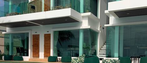 Une maison moderne à plusieurs étages, dotée d’une piscine, de grandes baies vitrées et d’un espace salon extérieur.