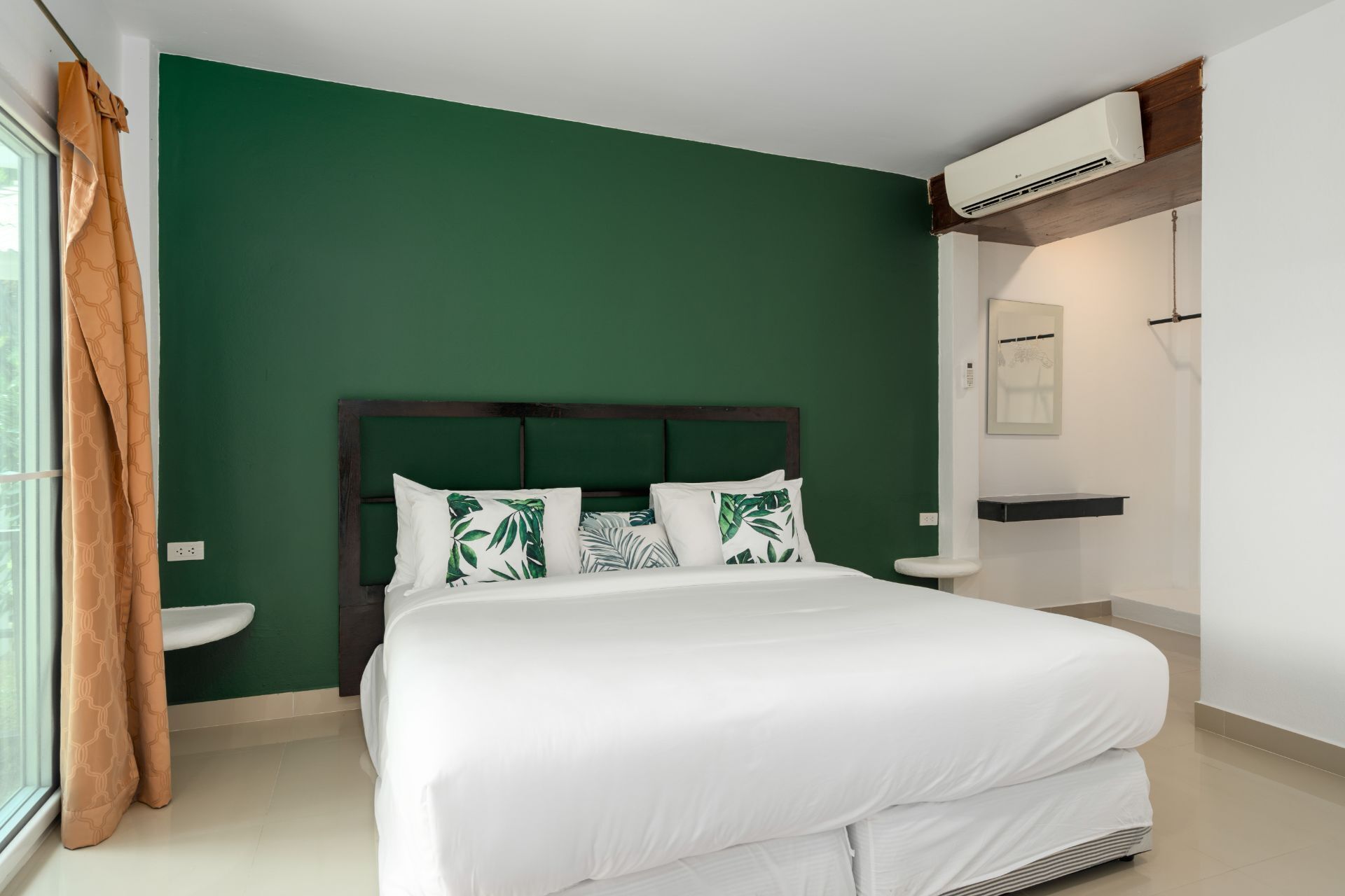 A bedroom with a bed, a nightstand, a window with curtains, and an air conditioning unit.