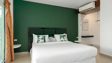 A bedroom with a bed, a nightstand, a window with curtains, and an air conditioning unit.