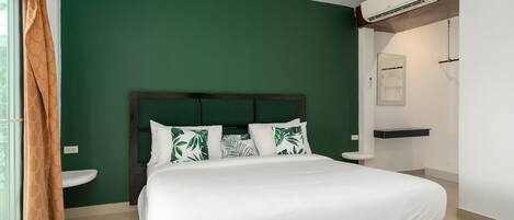 A bedroom with a bed, a nightstand, a window with curtains, and an air conditioning unit.