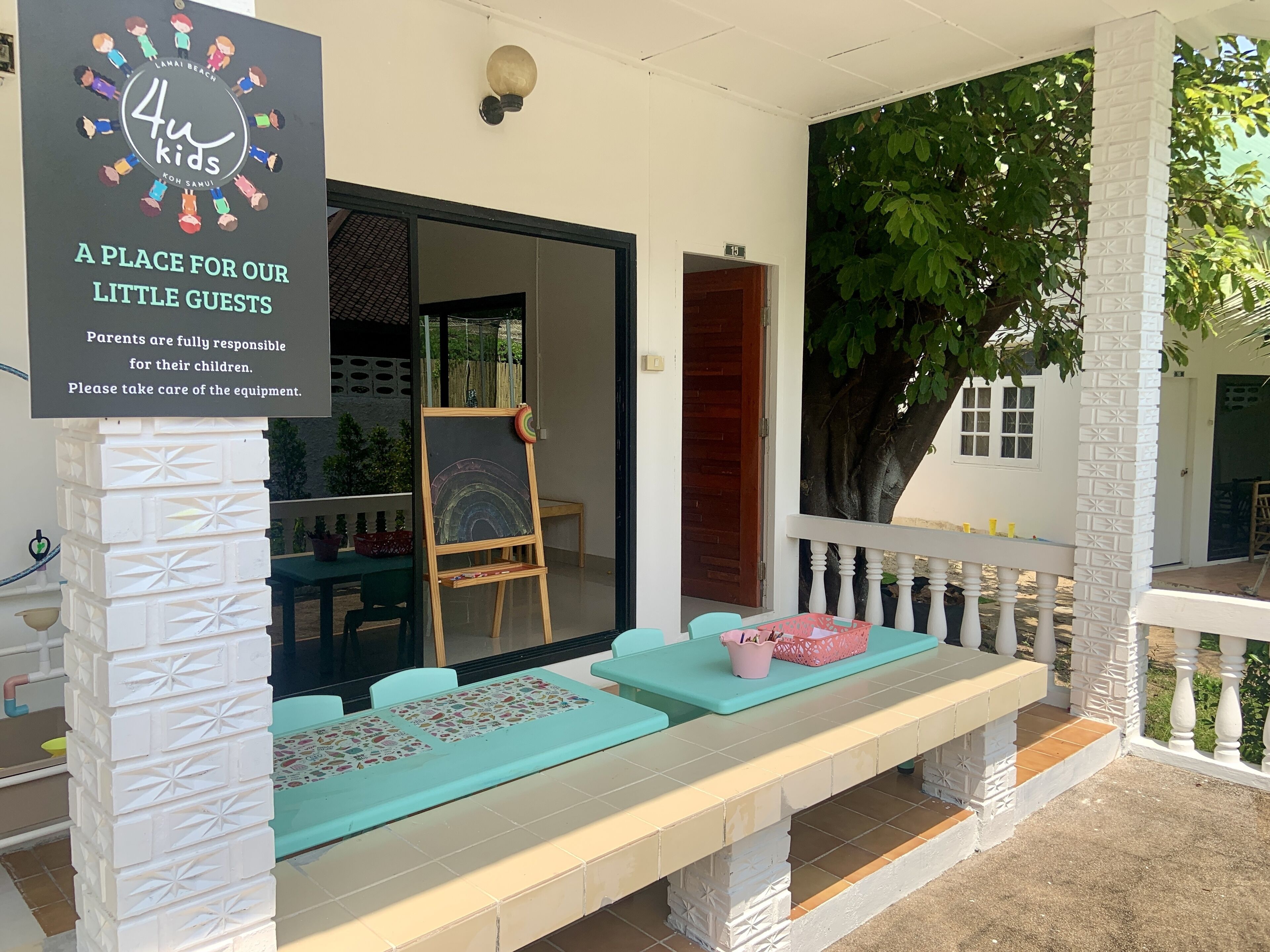 Zona de juegos infantiles con un letrero, una pizarra y un banco.