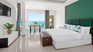 A modern bedroom with a large bed, a TV, a dining area with a view of the ocean, and a balcony. - 4U Resort Samui (Koh Samui)