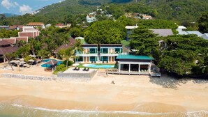 A beachfront property with a swimming pool, beach umbrellas, and a covered patio. - 4U Resort Samui (Koh Samui)
