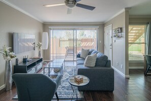 Relax in this stylish living room with a comfortable sofa, flat-screen TV, and sliding glass door leading to a patio area.