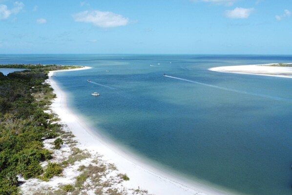 Un paysage côtier caractérisé par une plage de sable, des eaux d’un bleu limpide et une végétation clairsemée.