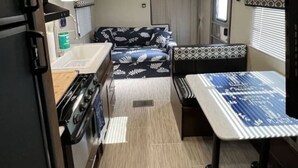 Une cuisine compacte pour camping-car, équipée d’une cuisinière, d’un four à micro-ondes et d’un évier.