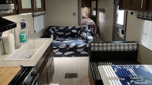 Une cuisine compacte pour camping-car, équipée d’une cuisinière, d’un évier et d’un four à micro-ondes.