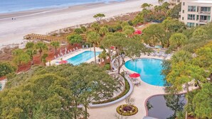 Un resort con dos piscinas, una playa y vista al océano.