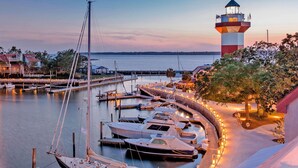 Un puerto deportivo con barcos amarrados, un faro y un edificio con terraza.
