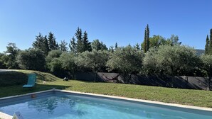 A rectangular swimming pool with clear blue water, surrounded by a grassy area and trees.