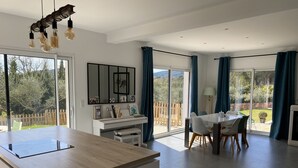 A modern kitchen with a large island, dining area with chairs, and a view of the outdoors.
