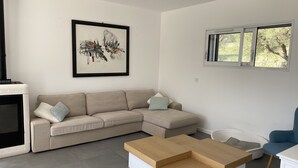A modern living room with a sectional sofa, a wooden coffee table, and a framed abstract painting on the wall.