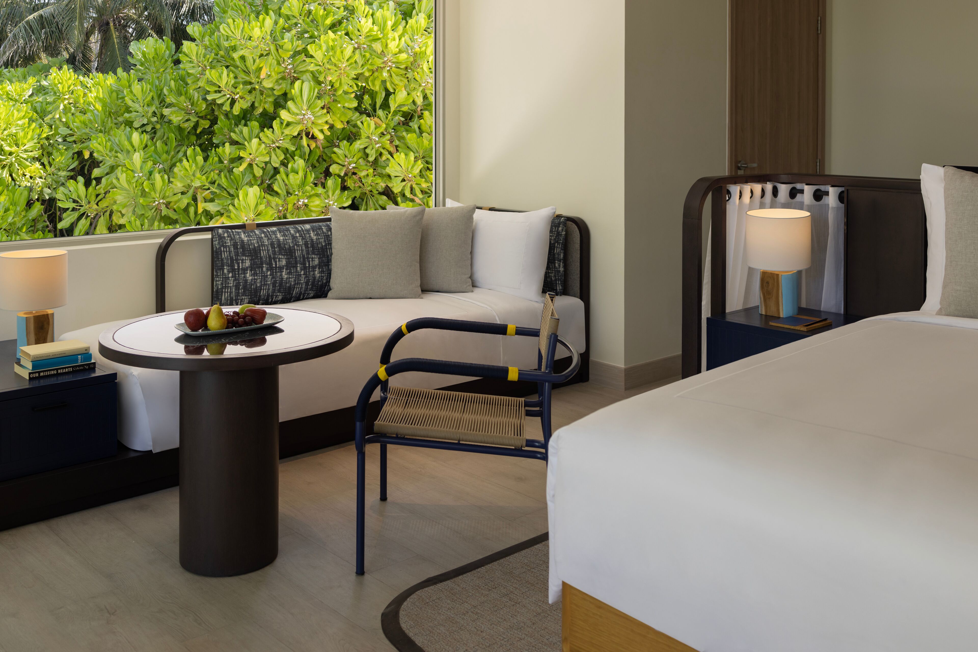 Una habitación de hotel con una cama, un sofá, una mesita con fruta y una silla.