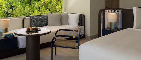 Una habitación de hotel con una cama, un sofá, una mesita con fruta y una silla.