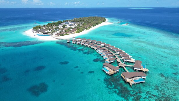 An overwater bungalows resort with a pier connecting to a small island, clear turquoise waters, and a white sandy beach. - Avani+ Fares Maldives Resort (Fares)