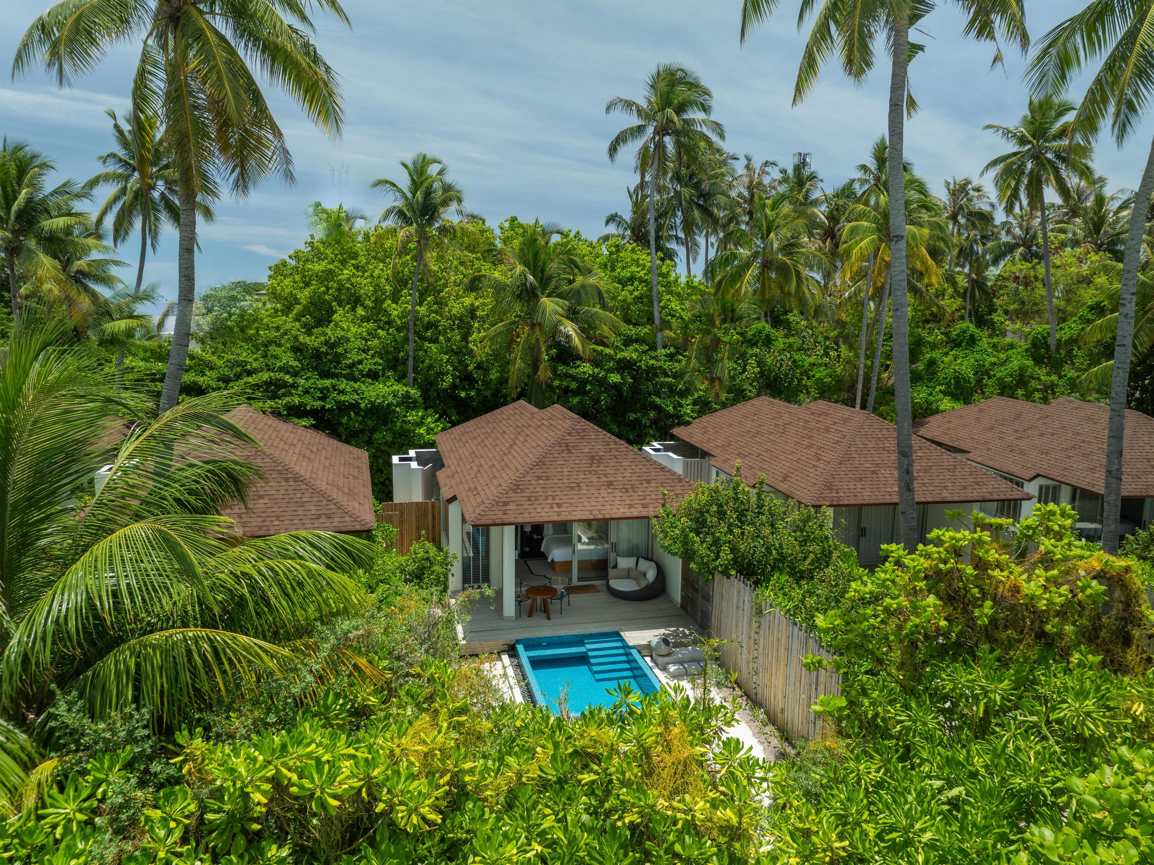 A resort with multiple bungalow-style accommodations, a swimming pool, and lush tropical vegetation.