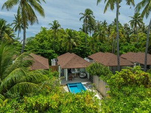 Un resort con varias cabañas tipo bungalow, una piscina y exuberante vegetación tropical.