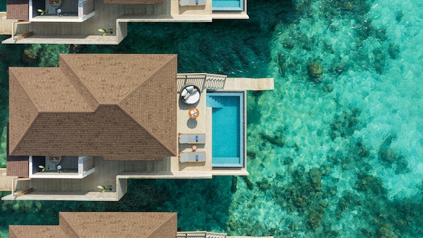 An aerial view of a resort with overwater bungalows, a central pool, and clear turquoise water. - Avani+ Fares Maldives Resort (Fares)