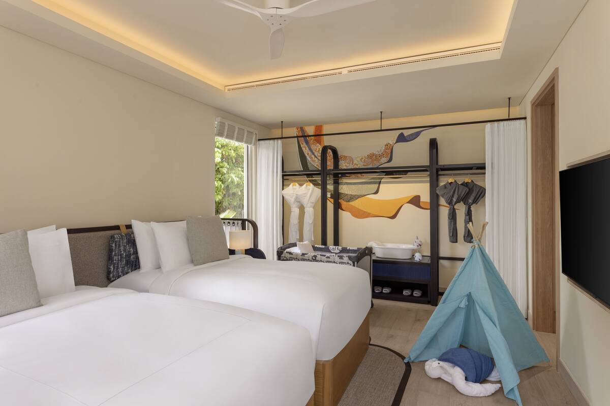 A hotel room with two beds, a tent, a TV, and a window with curtains.