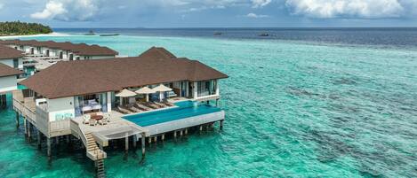 Wasserbungalows mit Infinity-Pools, Holzdeck-Geländern und Liegestühlen.