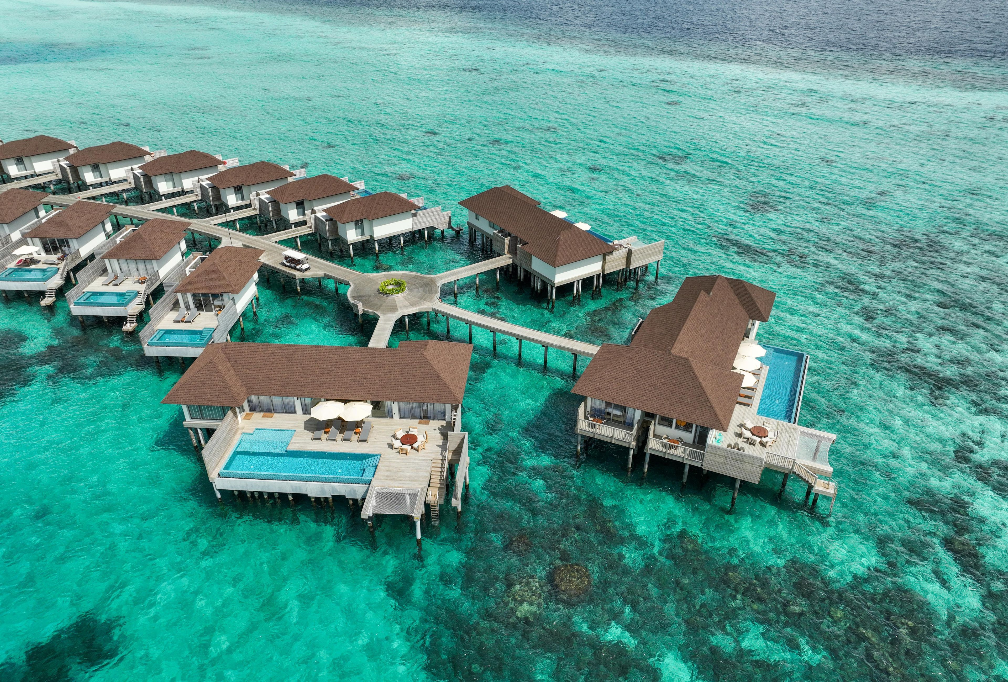 An overwater resort with multiple bungalow-style accommodations connected by walkways.
