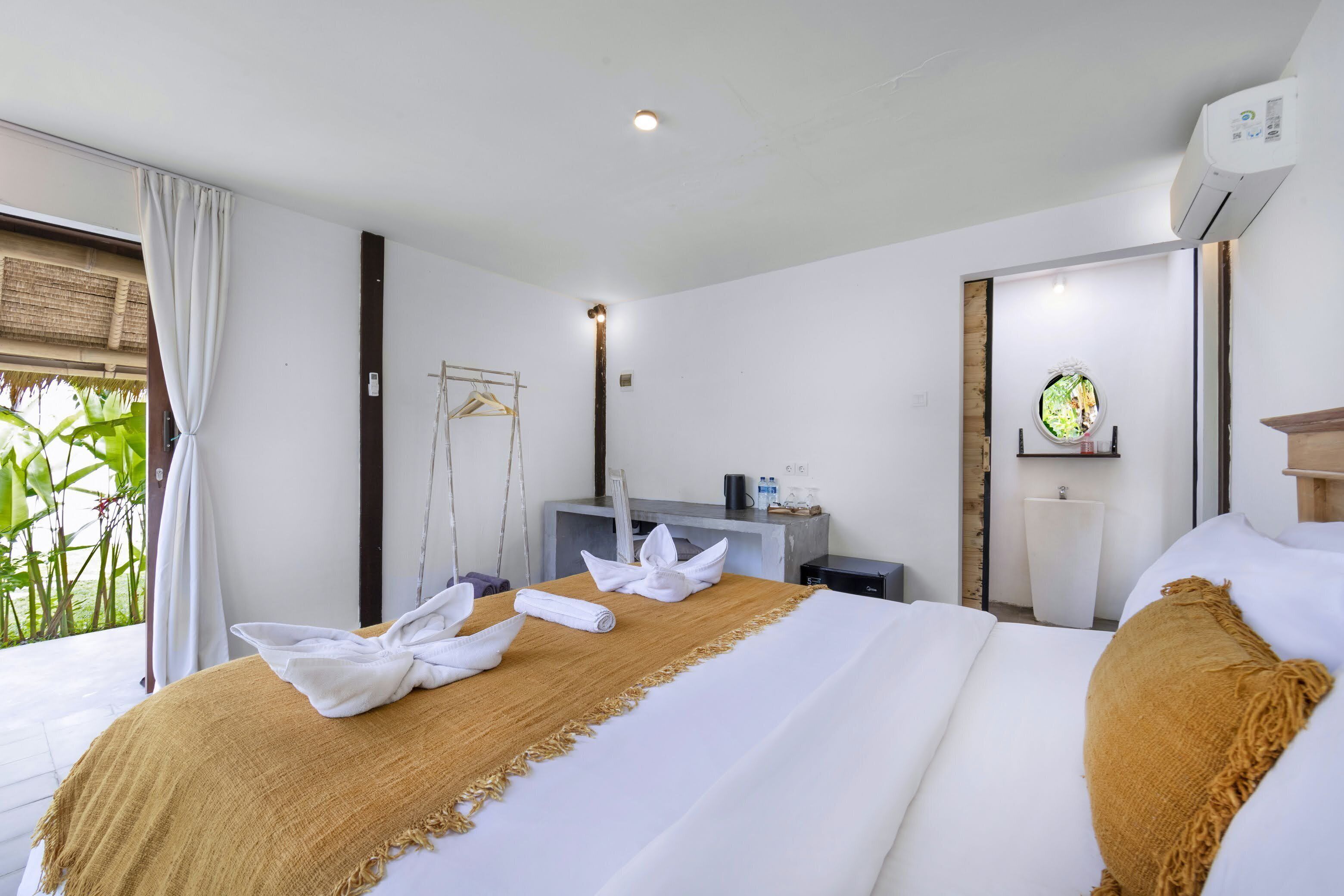 A hotel room with a bed, a desk, and a window with curtains.