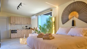 Een moderne slaapkamer met een groot bed, een ventilator naast het bed en uitzicht op de omgeving.
