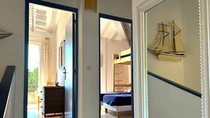 Ein Zimmer mit einem Etagenbett, einer Kommode und einer Segelbootsdekoration an der Wand.