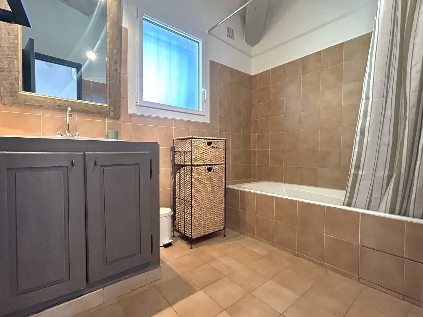 Un baño con bañera, ventana y perchero.