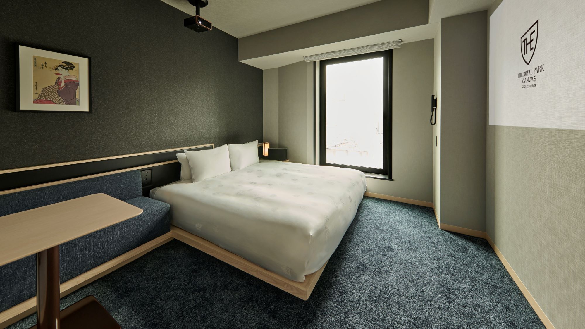 Een hotelkamer met een bed, een bureau, een stoel, een raam en een kunstwerk aan de muur.